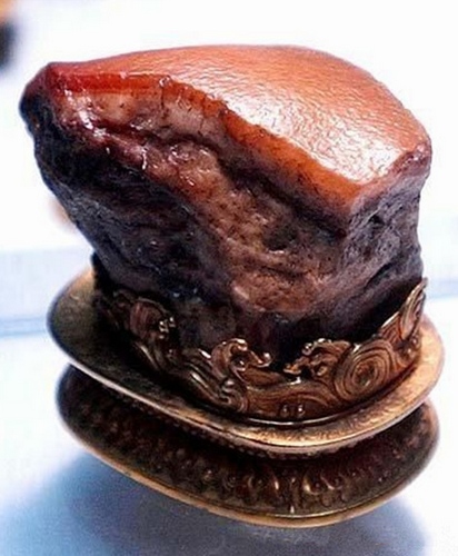 Esta pieza conocida como "piedra en forma de carne" se asemeja a la carne de cerdo guisada. No sólo son las capas de grasa y carne limpia claramente definidas, sino también en el tratamiento de los poros de la piel. La obra se exhibe en el Museo Nacional del Palacio de Taipei, en Taiwán. 