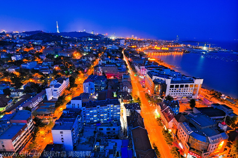 Vista nocturna de la ciudad de Qingdao, provincia de Shandong. Como uno de los más famosos ciudades costeras de China, Qigndao tiene el puente sobre el mar más largo del mundo. Custodiada por el mar por tres puntos cardinales, Qingdao está considerada una de las mejores ciudades para vivir en China. [Foto: IC] 