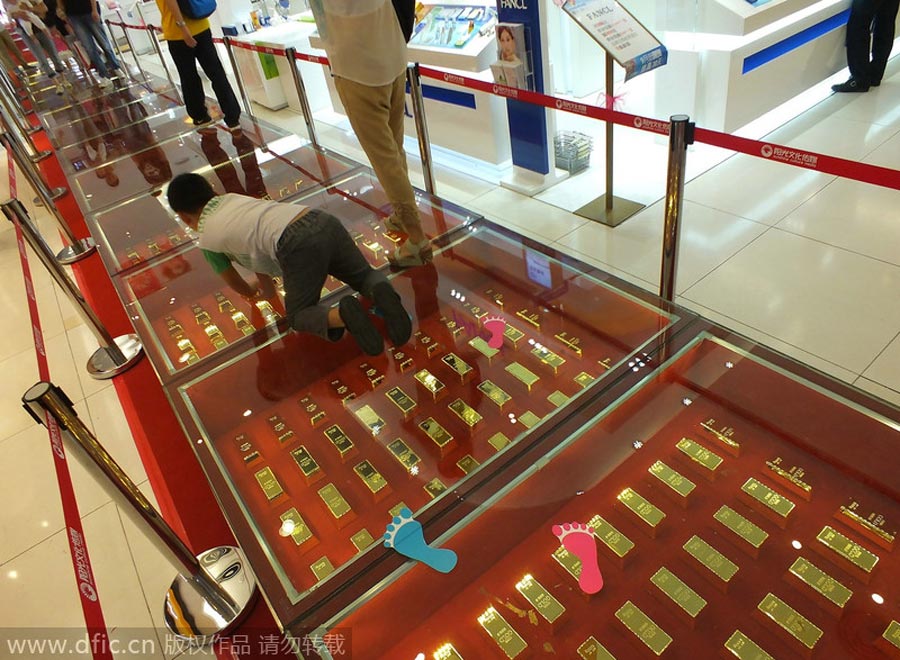 Niños juegan sobre la pasarela de lingotes de oro en un centro comercial de Yichang, Hubei, el 21 de septiembre de 2014. [Foto/IC]