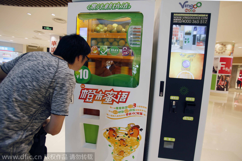Un cliente observa una máquina expendedora que vende jugo natural de naranja. Al momento, esta máquina exprime las naranjas almacenadas. Shanghai. China. [Foto: IC]