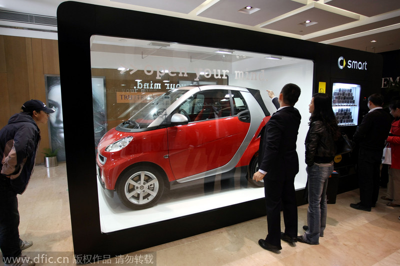 Interesados observan un automóvil Smart, exhibido dentro de una vitrina en forma de máquina expendedora. Jiangsu, China. [Foto: IC]