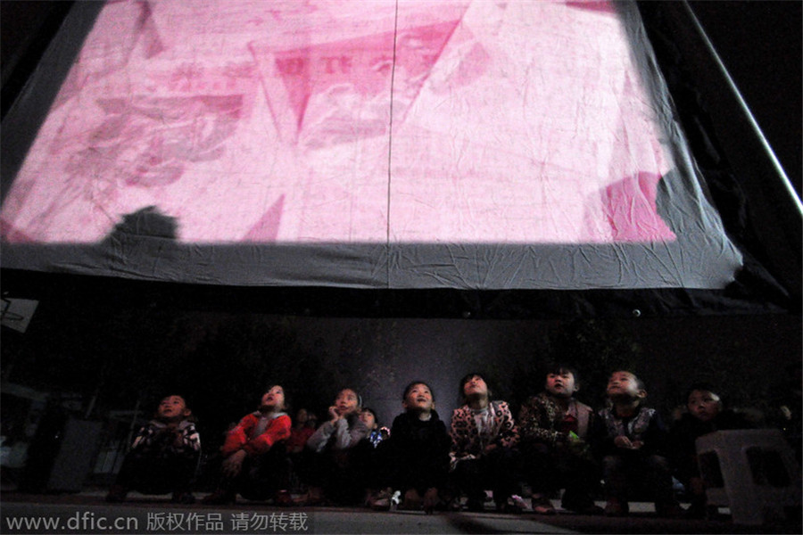 Niños en una aldea ven la película Jingzhong (la campana de alarma). [Foto / IC]