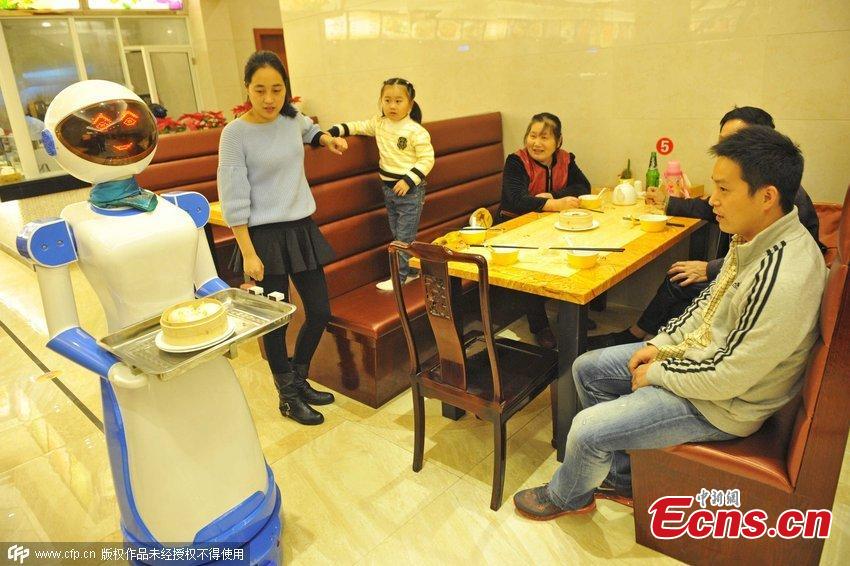 Un camarero robot sirve a los comensales en un restaurante de Ningbo. Los robots pueden reproducir 40 frases cortas y sencillas como "Por favor, disfrute de su comida" o "Lo siento, que estoy ocupado trabajando". [Foto / CFP]