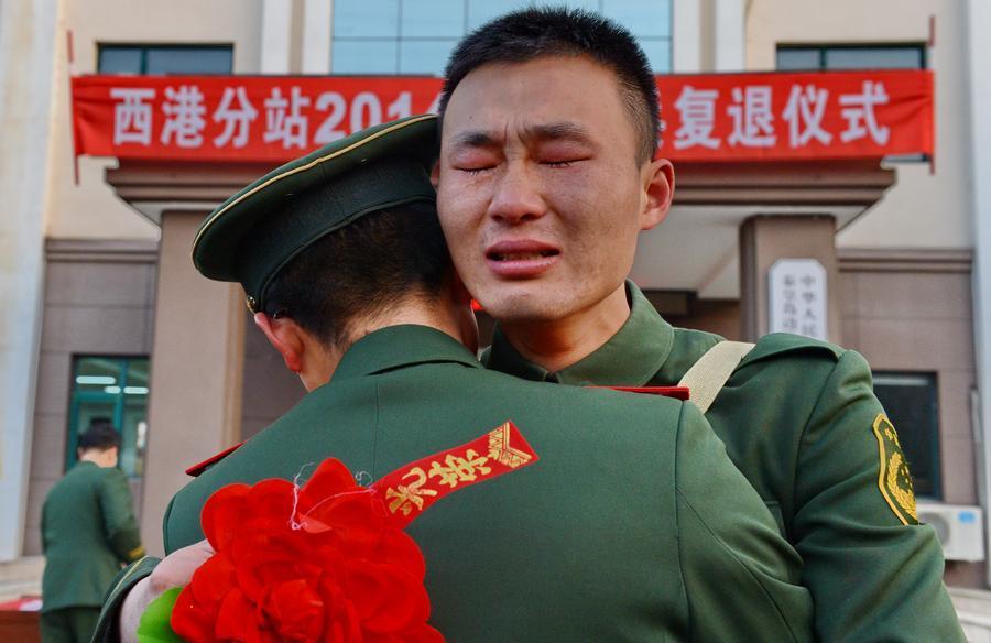 En el momento de despedirse y regresar a casa, un recluta abraza a su compañero de campaña. [Foto: Xinhua]