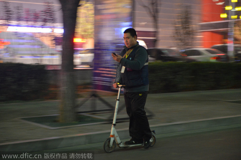 Li Xiaodong comprueba su teléfono en su scooter, en Shijiazhuang, provincia de Hebei, el 17 de diciembre de 2014. [Foto/IC]