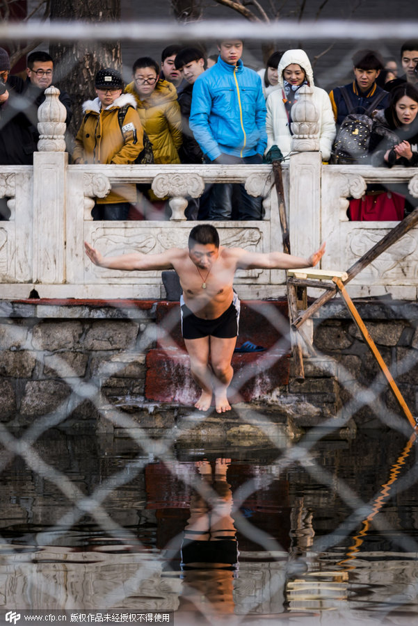 Los turistas observan a un hombre que salta a las aguas gélidas. [Foto/CFP]