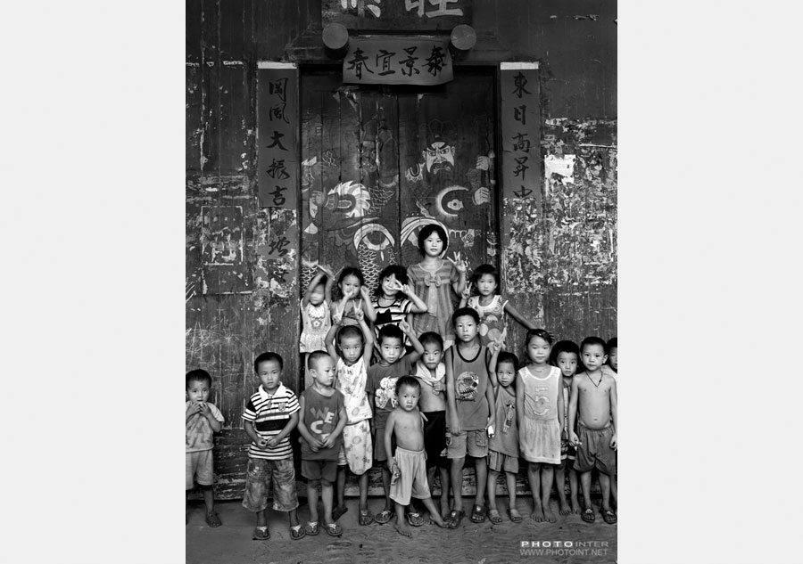 Un grupo de niños posan delante de una puerta antigua decorada con los dioses de las puertas en el condado Ningyuan de la provincia de Hunan, el 4 de septiembre de2011. [Fotografía de Yin Ganjiang/photoint.net]