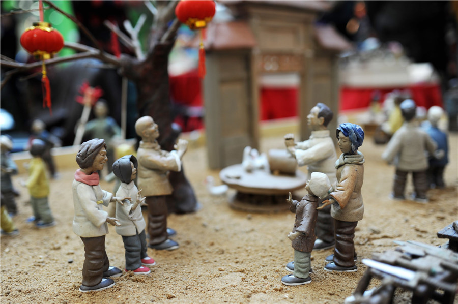 Estatuillas de unos vecinos saludándose en la calle hechas de arcilla. [Fotografía por Wang Haibin/Asianewsphoto]