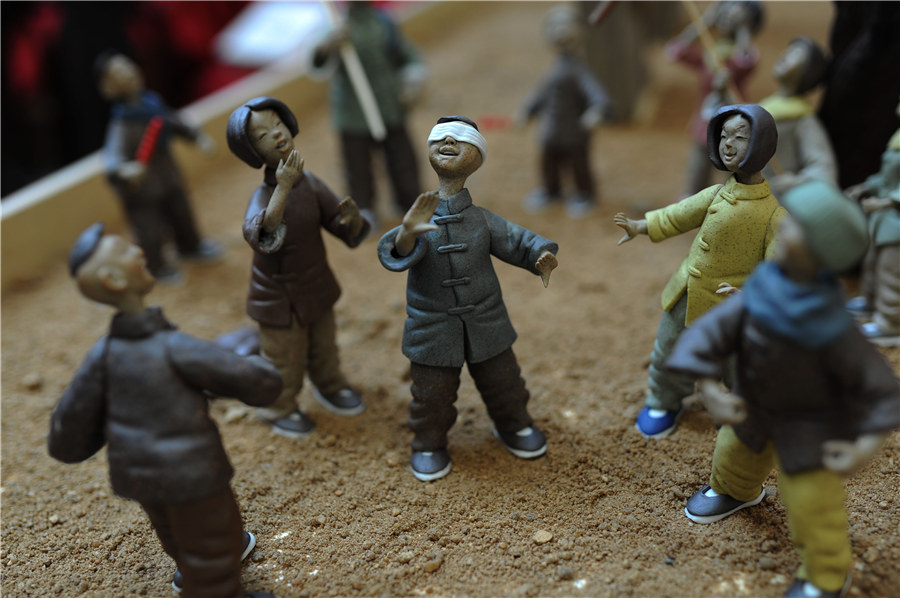 Estatuillas de unos niños jugando a la “gallinita ciega” hechas de arcilla. [Fotografía por Wang Haibin/Asianewsphoto]