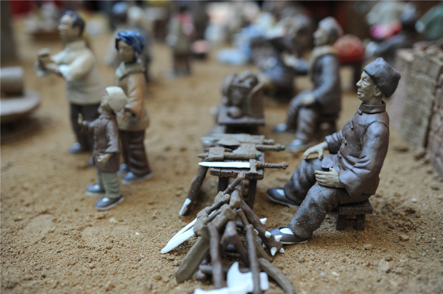 Estatuillas de unos vendedores de herramientas del campo y armas hechas de arcilla. [Fotografía por Wang Haibin/Asianewsphoto]