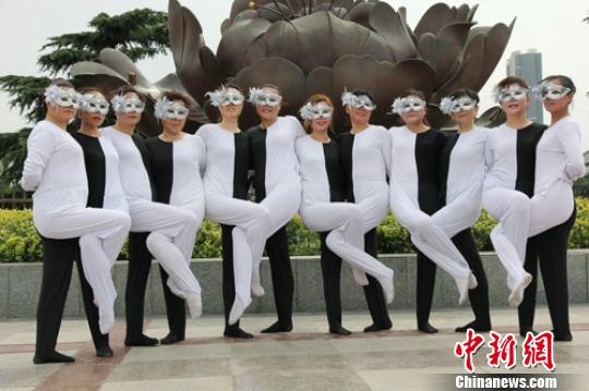 Bailarines de mediana edad con trajes bicolores y máscaras plateadas durante una actuación. [Foto/Zhengzhou Evening News]