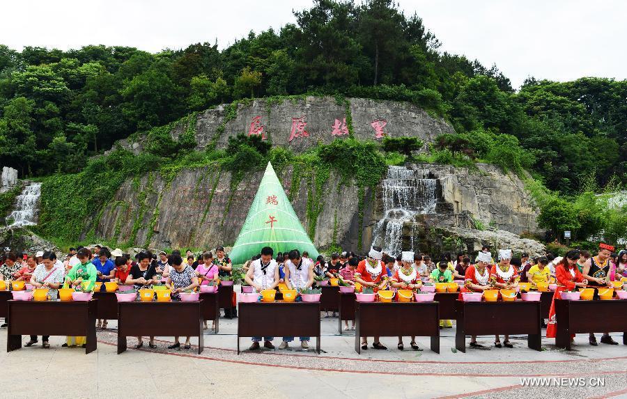 Residentes locales participan en un concurso de hacer Zongzi, una bola de masa de arroz glutinoso envuelta en hojas de bambú o de caña, para celebrar el Festival del Barco de Dragón en Zigui, provincia de Hubei, el 16 de junio de 2015.[Foto/Xinhua]