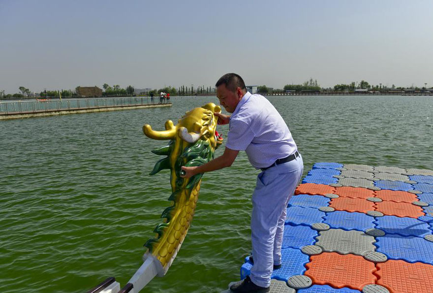 Peng Jiabai instala la cabeza de dragón de plástico en un barco de dragón en la ciudad de Chengdu, provincia de Sichuan, el 12 de junio de 2015. 