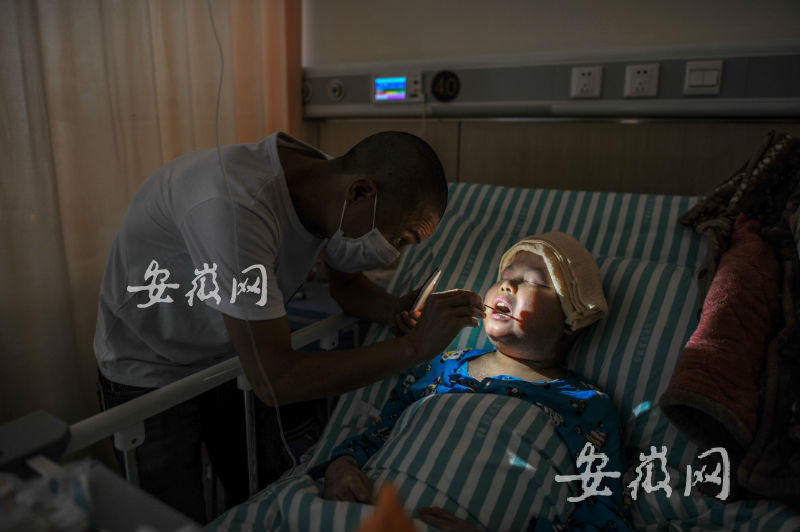 En el hospital, Cheng Liushun, uno de los padres del grupo, ayuda a limpiar residuos a su hijo con un palito de algodón.