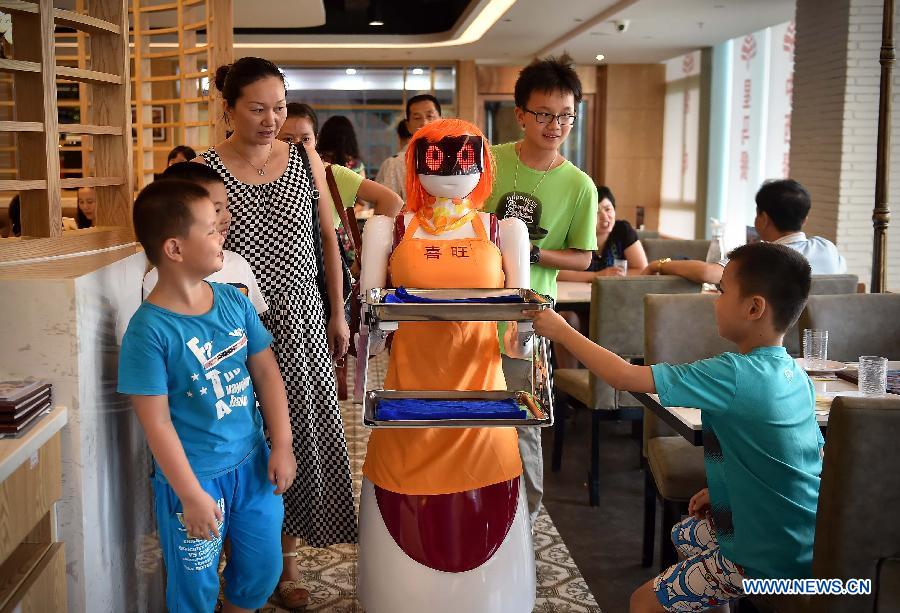 Los clientes observan a la camarera robot en Haikou, capital de la provincia de Hainan, el 3 de agosto de 2015. La camarerao robot trabaja en un restaurante de Haikou. [Foto/Xinhua]