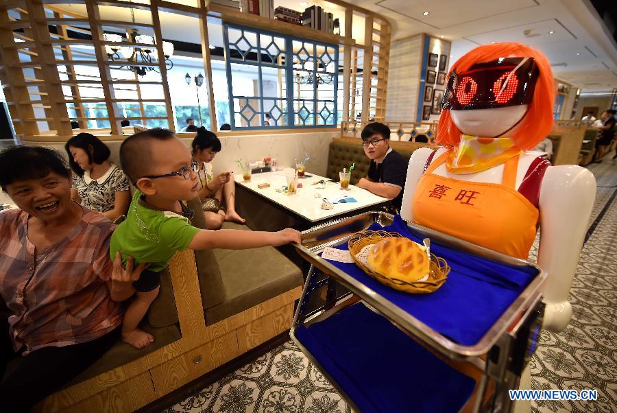 Un niño curioso toca a la camarera robot en Haikou, capital de la provincia de Hainan, el 3 de agosto de 2015. La camarerao robot trabaja en un restaurante de Haikou. [Foto/Xinhua]