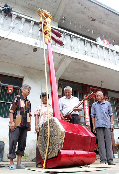 Ji Jiarong (el hombre de blanco), de 74 años, muestra un erhu gigante que él mismo fabricó en la aldea Liuji de Baidian, condado Haian, provincia de Jiangsu, el 21 de agosto de 2015.