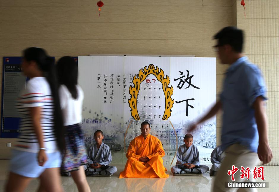La gente pasa junto a varios monjes sentados en el suelo en un edificio de oficinas. [Foto/Ecns.cn]