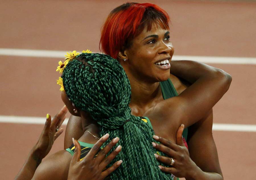 Shelly-Ann Fraser-Pryce de Jamaica abraza a Blessing Okagbare de Nigeria durante la carrera femenina de 100 metros en el Mundial de Atletismo de Pekín, 23 de agosto de2015. 