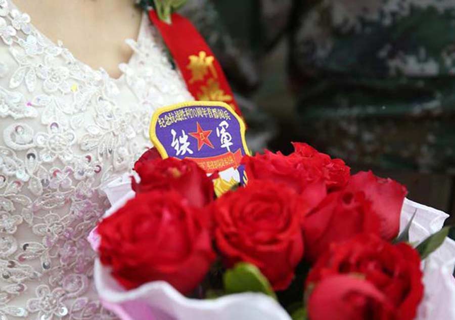 Una novia sostiene un ramo de flores durante la boda en grupo antes del desfile militar en la Plaza de Tian'anmen el 3 de septiembre de 2015. [Foto/81.cn]