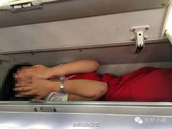 Una foto sin fecha muestra que una azafata de vuelo escondida en un compartimento superior de equipaje de mano con las manos tapándose la cara. [Foto: weibo.com]