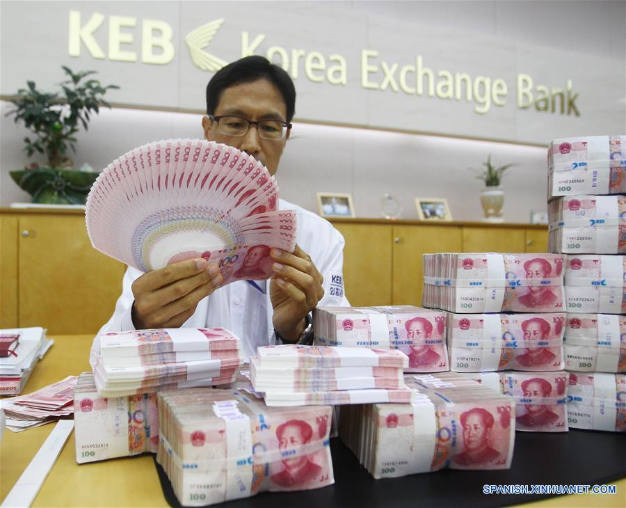 La foto tomada el pasado 27 de junio del año 2014 muestra a un empleado de un banco en la ciudad de Seúl mostrando unos billetes de Renminbi. El Fondo Monetario Internacional anunció el pasado 30 de noviembre de 2015 la inclusión el renminbi en la cesta de monedas de Derechos Especiales de Giro.
