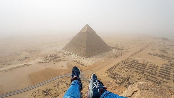 Un turista escala la pirámide de Keops para hacer fotos