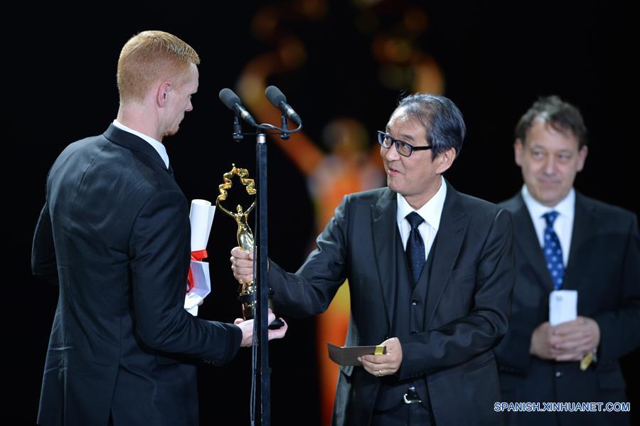 El director Yojiro Takita (d-frente), entrega el trofeo del Premio Tiantan por Mejor Director por la película "The Idealist", durante la ceremonia de clausura del VI Festival Internacional de Cine de Beijing (BJIFF, por sus siglas en inglés), en Beijing, capital de China, el 23 de abril de 2016. (Xinhua/Chen Bin)