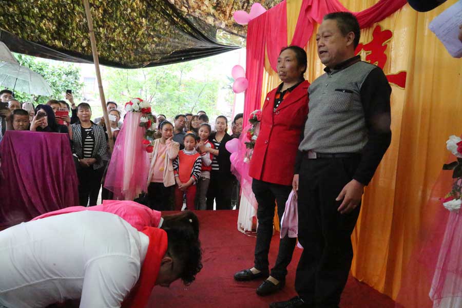 Tang y su esposa se arrodillan ante sus padres en el día de la boda. 