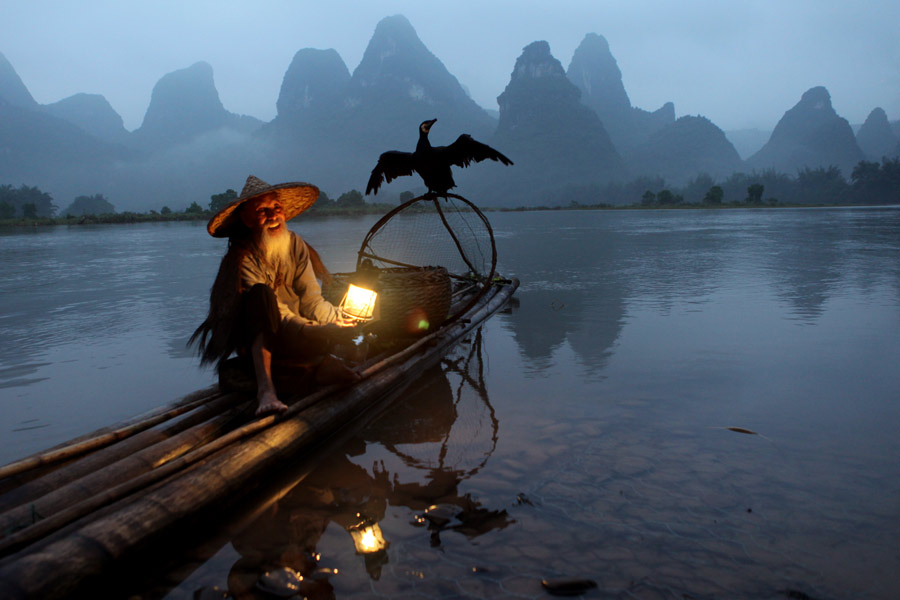 El anciano posa con sus cormoranes y una linterna en el río Lijiang a su paso por la ciudad de Guilin, región autónoma Zhuang de Guangxi. [Fotografía de Huo Yan/chinadaily.com.cn]