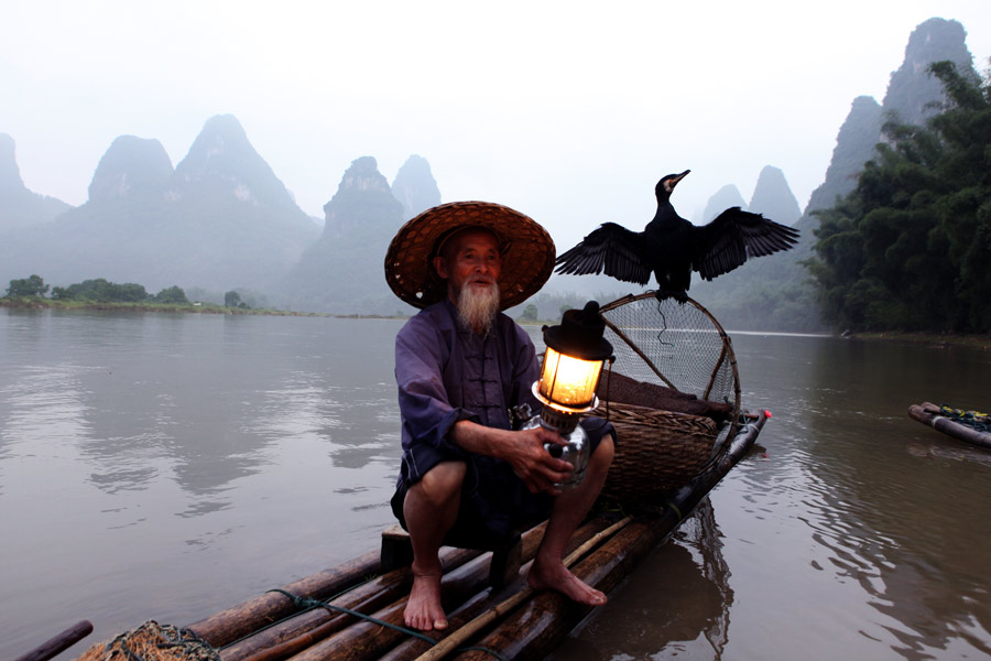 Huang Yuechuang sostiene una linterna en el río Lijiang de la ciudad de Guilin, región autónoma Zhuang de Guangxi. [Fotografía de Huo Yan/chinadaily.com.cn]