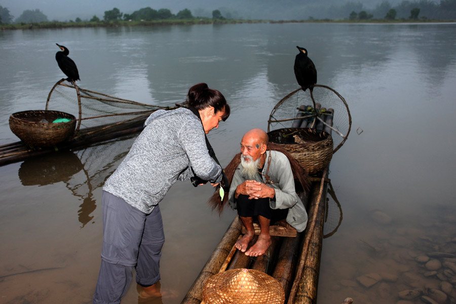 Una fotógrafa enseña al anciano su foto en la cámara. [Fotografía de Huo Yan/chinadaily.com.cn]