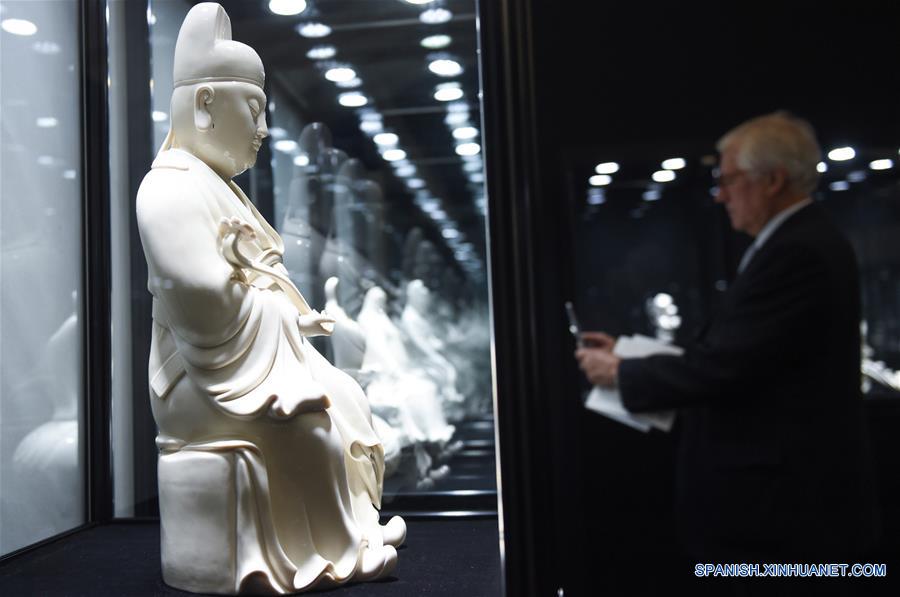  BEIJING, mayo 26, 2016 (Xinhua) -- Un hombre toma una fotografía frente a una figura de porcelana exhibida en la Exposición de Arte de Porcelana de Dehua, en Beijing, capital de China, el 26 de mayo de 2016. Dehua, conocida como una de las bases de la porcelana de China, cuenta con una larga historia de eleboración de alfarería. La exposición es una actividad del foro de cultura China-Francia. (Xinhua/Luo Xiaoguang) 