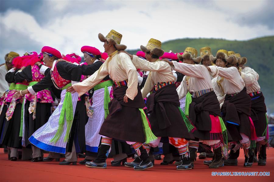 Personas interpretan un baile tradicional durante un festival de carreras de caballos en Shangri-la, Prefectura Autónoma Tibetana de Diqing, en la provincia de Yunnan, en el suroeste de China, el 9 de junio de 2016. Un total de 194 caballos participarán en el festival étnico tradicional de tres días de duración, que dio inicio el jueves. (Xinhua/Zhou Lei)