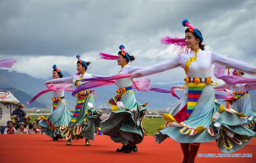 Personas interpretan un baile tradicional durante un festival de carreras de caballos en Shangri-la, Prefectura Autónoma Tibetana de Diqing, en la provincia de Yunnan, en el suroeste de China, el 9 de junio de 2016. Un total de 194 caballos participarán en el festival étnico tradicional de tres días de duración, que dio inicio el jueves. (Xinhua/Zhou Lei)