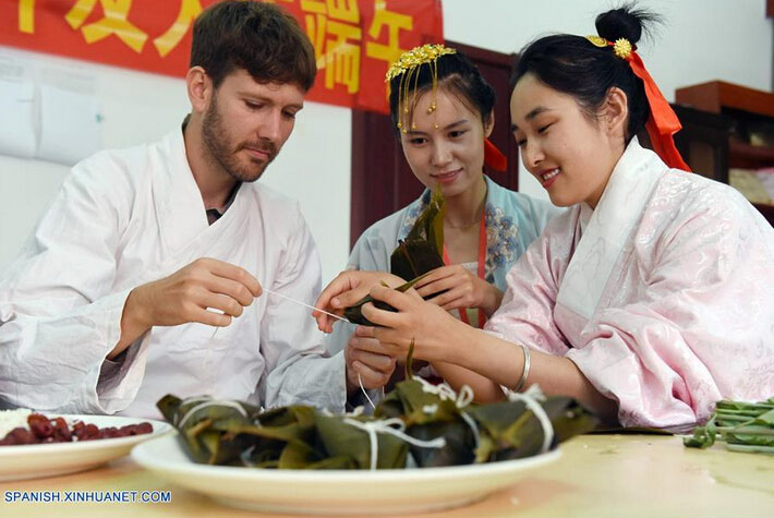 Matthew (i) de Estados Unidos de América, aprende a elaborar Zongzi, una bola de masa de arroz glutinoso envuelta en holas de bambú u hojas rojas, con motivo del próximo Festival del Bote de Dragón o Duanwu en chino, en Cangzhou, provincia de Hebei, en el norte de China, el 8 de junio de 2016. El Duanwu se celebrará el 9 de junio este año. (Xinhua/Fu Xinchun)