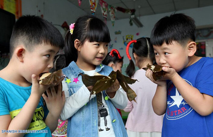  Li Qingji (i), Deng Jiahe (c) y Cao Heteng (d) comen Zongzi, una bola de masa de arroz glutinoso envuelta en holas de bambú u hojas rojas, con motivo del próximo Festival del Bote de Dragón o Duanwu en chino, en un jardín de niños en Zaozhuang, provincia de Shandong, en el este de China, el 8 de junio de 2016. El Duanwu se celebrará el 9 de junio este año. (Xinhua/Sun Zhongzhe)