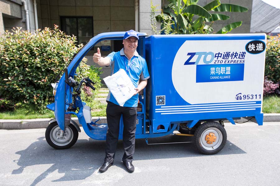 Lai Meisong, presidente ejecutivo de ZTO Express, de pie frente a un triciclo de mensajería con un paquete en la mano durante la Cumbre Mundial de Logística Inteligente 2016 en Hangzhou, capital de la provincia de Zhejiang, el 13 de junio de 2016. [Foto/VCG]
