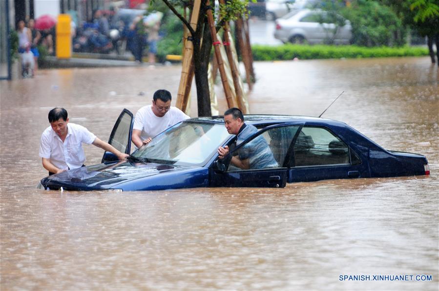 Rescatistas empujan un vehículo atrapado en un camino inundado en Jiujiang, provincia de Jiangxi, en el este de China, el 15 de junio de 2016. Una lluvia torrencial afectó el miércoles la ciudad. (Xinhua/Hu Guolin)