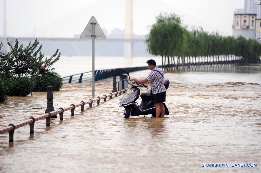 Un hombre sostiene su motocicleta en la línea ampliada sumergida de la Carretera Binjiang Oeste, en Liuzhou, en la Región Autónoma Zhuang de Guangxi, en el sur de China, el 15 de junio de 2016. Las autoridades locales de control de inundaciones y alivio de sequías pronosticaron que la sección de Liuzhou del río Liujiang se elevará a su nivel de advertencia de 82.5 metros aproximadamente a las 5 p.m. del miércoles. (Xinhua/Cheng Qun)