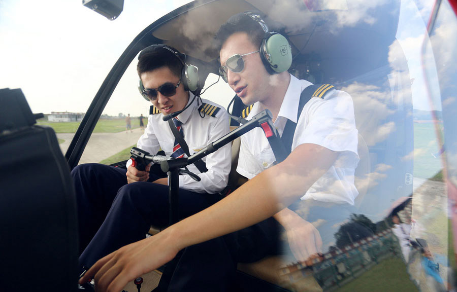 Dos pilotos de helicóptero posan para el anuncio de inscripción de una escuela de aviación civil de Chengdu, el 7 de junio de 2016. 