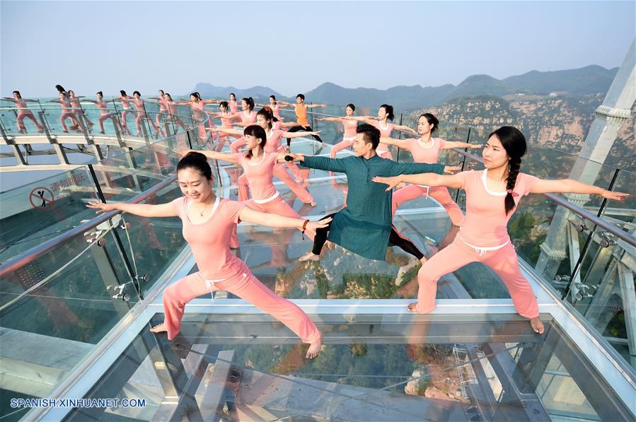 Personas practican yoga en una plataforma de cristal en Beijing