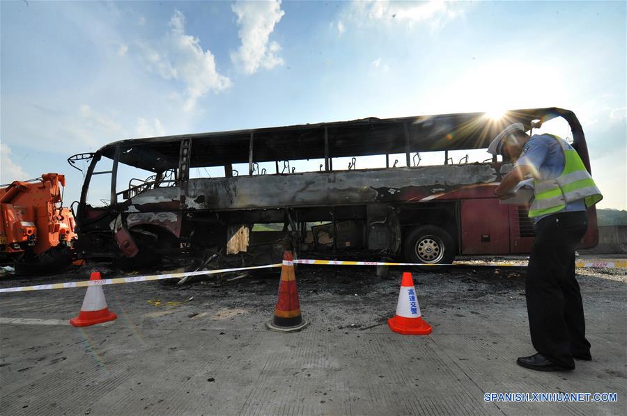 Un policía de tránsito examina un sitio del accidente en el condado de Yizhang, en la provincia central de Hunan, en China, el 26 de junio de 2016. Un incendio que redujo a un autobús turístico a una estructura carbonizada el domingo por la mañana ha provocado la muerte de al menos 35 personas, incluidos dos niños, en la provincia central china de Hunan, confirmaron las autoridades locales. El accidente se produjo hacia las 10:20 horas, cuando el autobús chocó contra las barreras de protección en una autopista de Yizhang. (Xinhua/Long Hongtao)