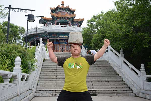 Cong Yan posa con una piedra de 40 kilos sobre la cabeza en la provincia de Jilin.