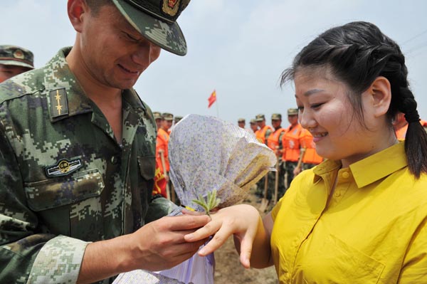 Xu Hao coloca un anillo de hierba en el dedo de su novia, Xiao Ruoyu, durante una boda especial en una zona afectada por las inundaciones en Wuwei, ciudad de Wuhu en la provincia de Anhui, el 9 de julio de 2016.[Foto/VCG]