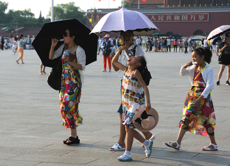 Turistas pasean por la plaza Tian´anmen con paraguas y helados para combatir el calor, el 6 de julio de 2016. [Foto/VCG]