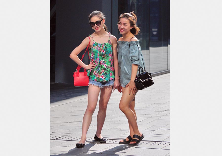 Dos mujeres con ropa de verano y gafas de sol se hacen una foto en Sanlitun de Beijing, el 6 de julio de 2016. [Foto/VCG]
