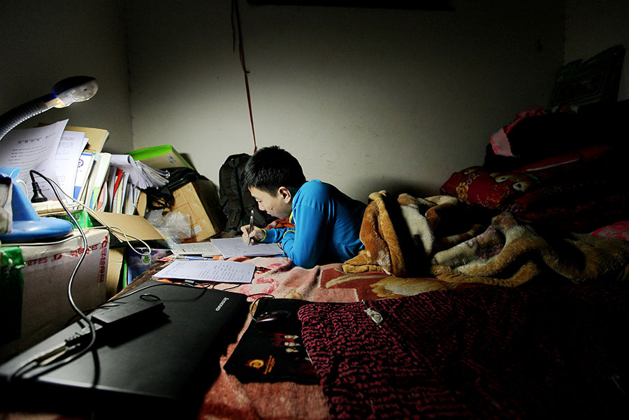 Zhu Zhiqiang estudia tumbado sobre su cama por la noche en una habitación de 10 metros cuadrados que alquila cerca de la escuela, el 19 de abril de 2016.