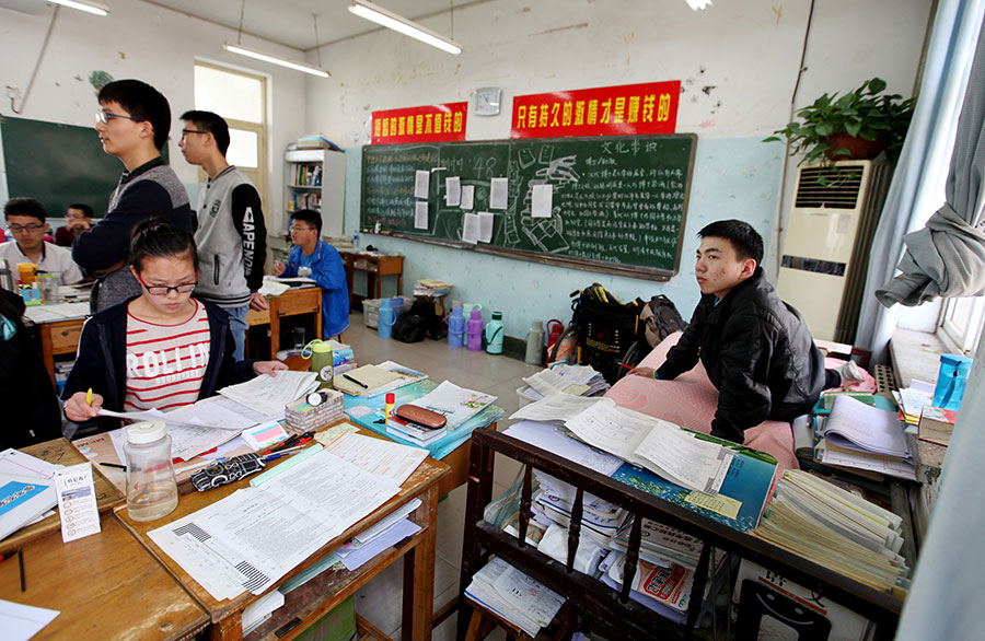 Foto de Zhu Zhiqiang (derecha) sentado en su cama en el aula, el 19 de abril de 2016.