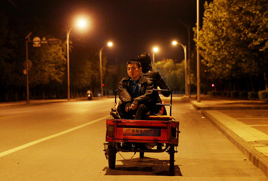 Zhu en la parte posterior del triciclo que su madre utiliza para regresar a casa por la noche, el 19 de abril de 2016. 